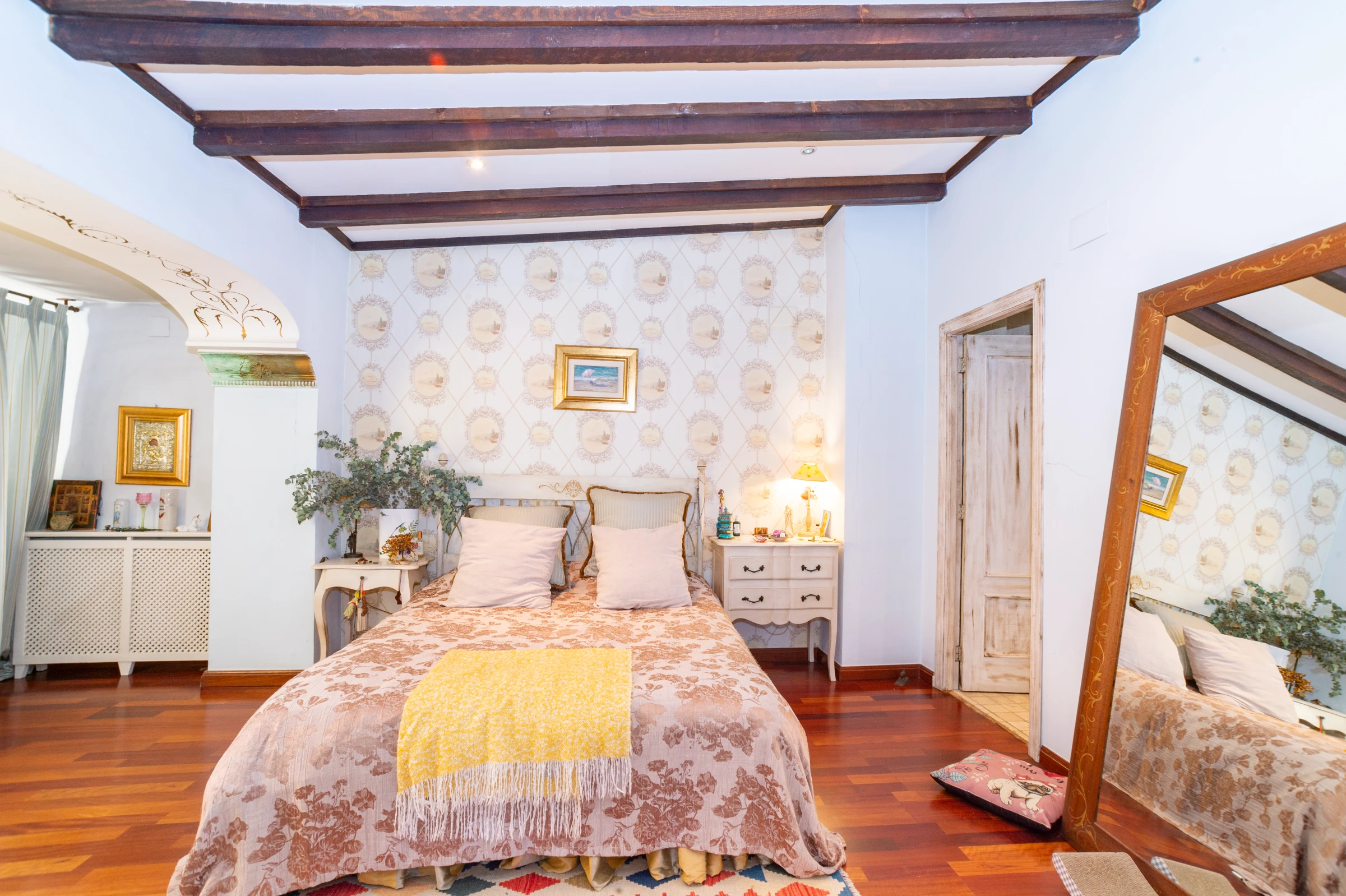 Dormitorio principal de un exclusivo dúplex histórico en El Carmen, Valencia, con vigas de madera vistas, suelo de madera y baño en suite.