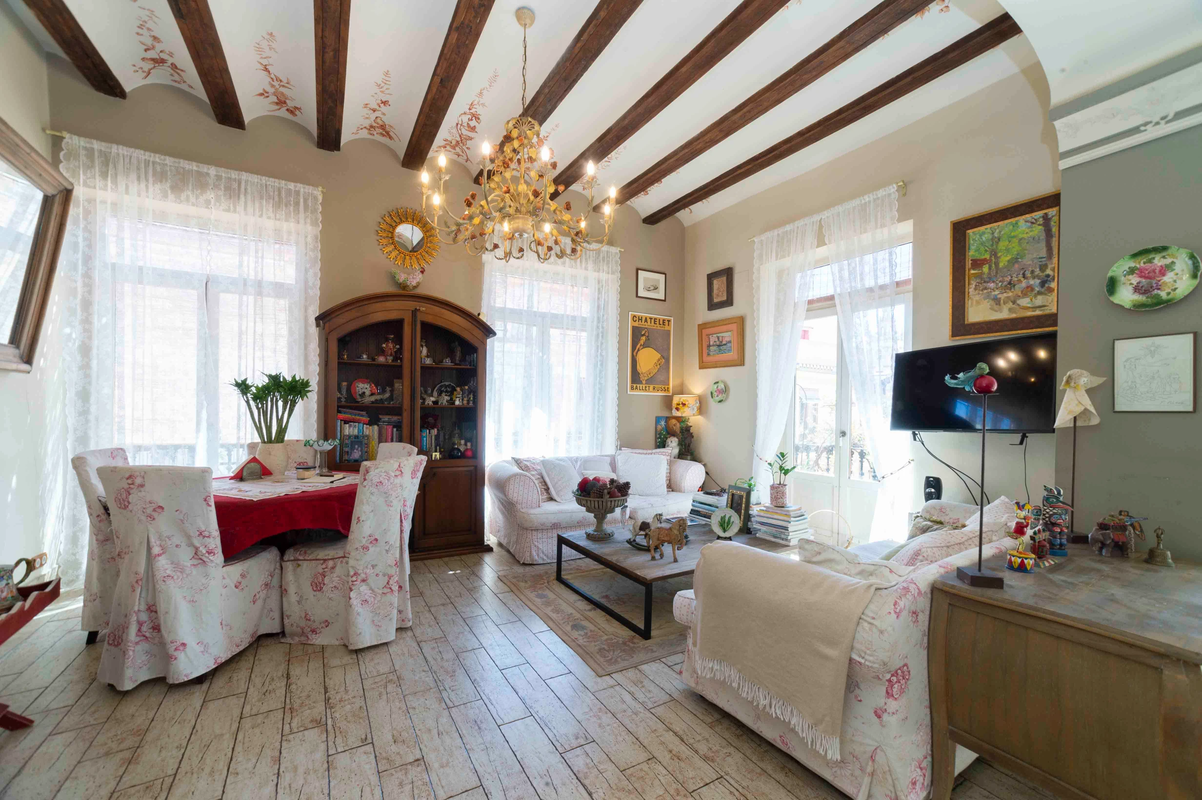 Amplio salón-comedor de un dúplex histórico en El Carmen, Valencia, con vigas de madera vistas y mucha luz natural.